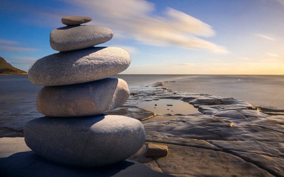 A peaceful image of stacked stones in front of a calm ocean